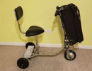 Right Side View Of The HandyScoot Lightweight Travel Mobility Scooter Shown With A Luggage Bag On The Front Luggage Attachment Shown In An Indoor Setting