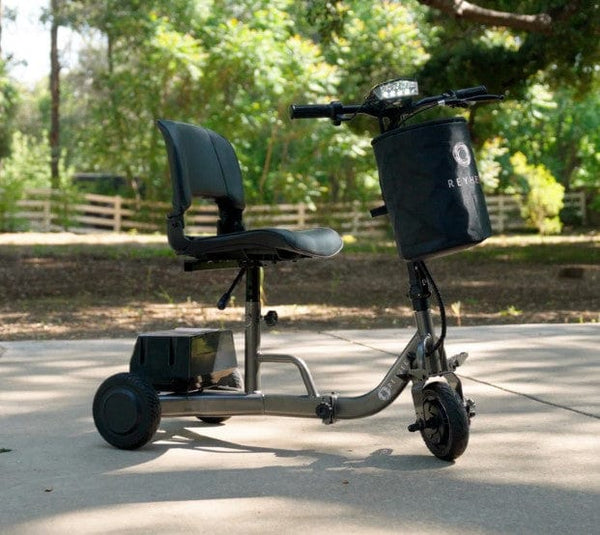 Right Side View Of The Reyhee Triad Compact Folding Electric Mobility Scooter Shown With The Gun Metal Colored Frame In An Outdoor Daytime Setting