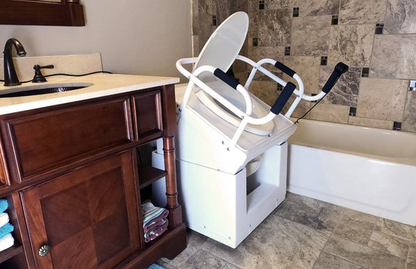 Right Side View Of The Throne Buttler Powered Toilet Lift Chair TLFE001 Shown In The Raised Position Over A White Toilet Bowl In A Bathroom Setting