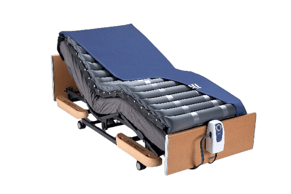 Right Side View Of The Wellell Domus 2 Alternating Pressure Redistribution Mattress Shown On An Adjustable Bed With The Control Unit Hanging Off The Footboard