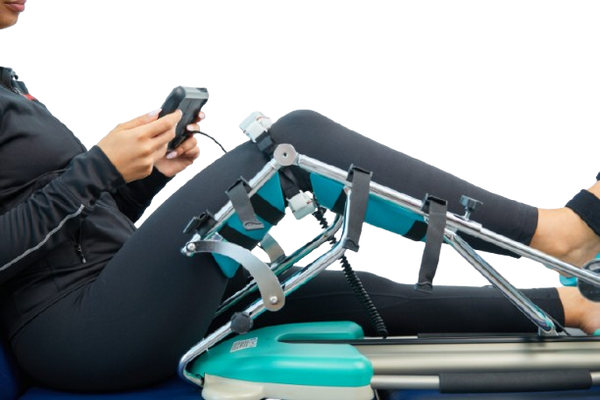 Side View Of A Woman Using The Kinetec Spectra Kompanion Knee CPM Machine With Tablet