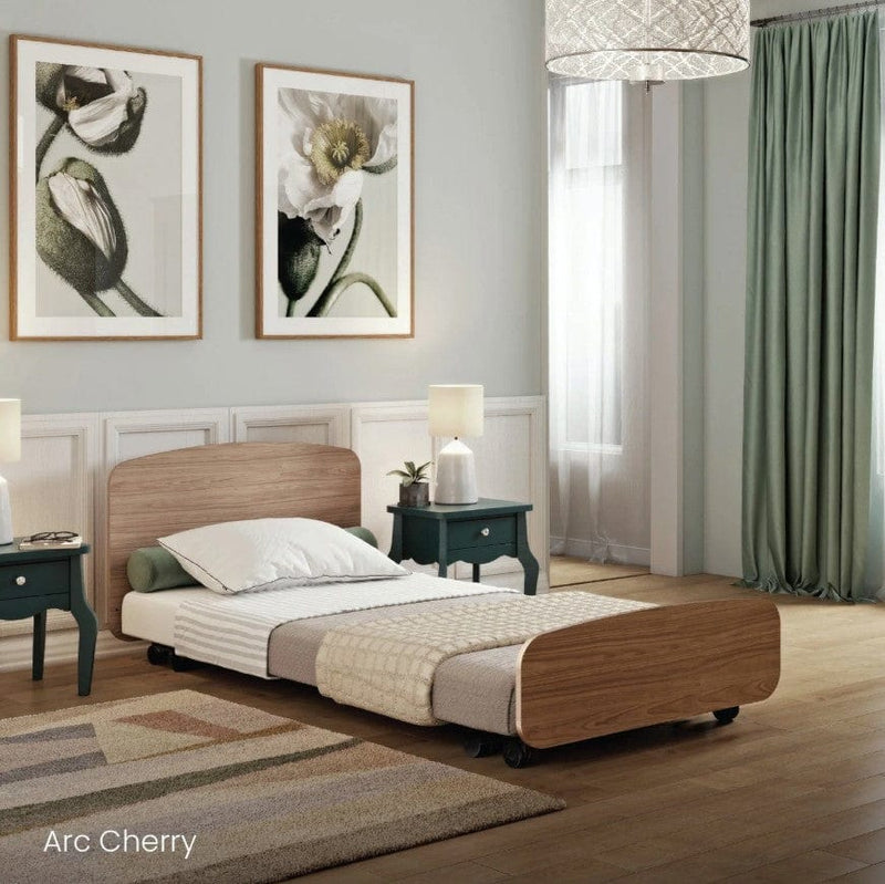 Side View Of The Accora Empresa 12-Function Hi Low Adjusting Nursing Bed Shown In Arc Design With Cherry Wood Finish In A Homecare Setting