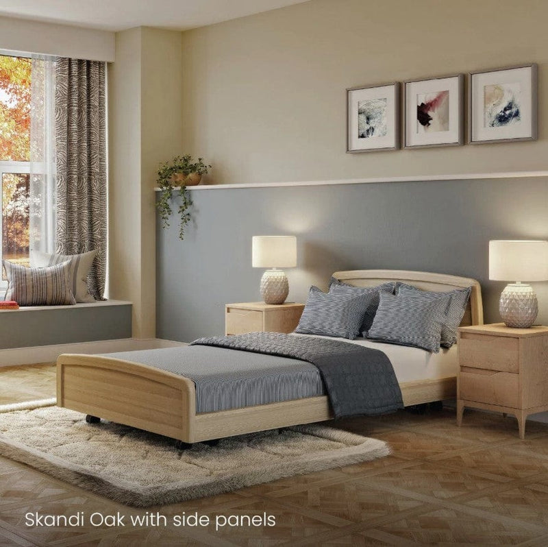 Side View Of The Accora Empresa 12-Function Hi Low Adjusting Nursing Bed Shown In Skandi Design With Oak Wood Finish In A Homecare Setting