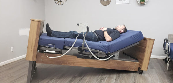 Side View Of The Med Mizer Active Care Deluxe Rotating Bed In The Trendelenburg Position In A Home Setting With A Man Lying Down In The Bed