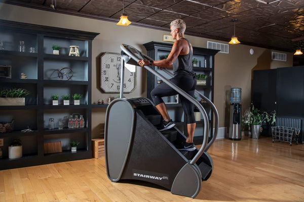 Side View Of The StairMaster Stairway GTL Stair Climber Shown With A Woman Operating The Climber In A Home Setting