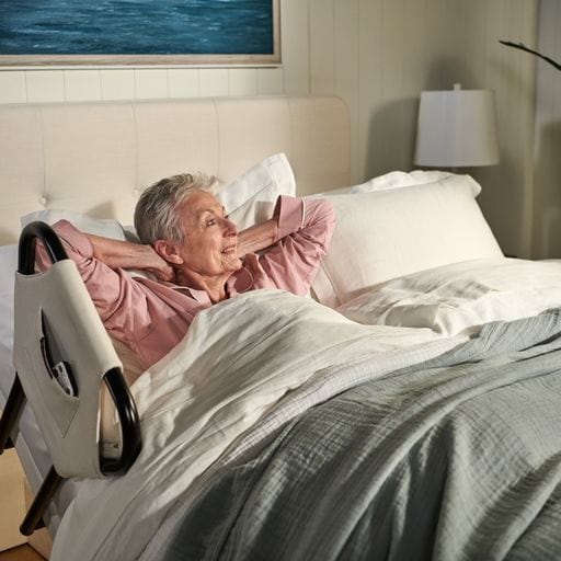 The Dawn House Bed Side View With Side Rail And Elderly Woman Waking Up