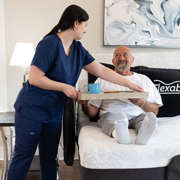 The Flexabed Hi Low Adjustable Bed Front Facing View With Side Rails And Side Rail Covers With Caregiver And Patient