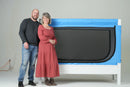 Two People Standing Next To The Safe Place Bedding Model 200 Safe Place Bed Shown In White Painted Frame And White Padding With Blue Cover