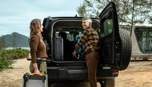 Two People With Luggage Near An Open Car Door In A Natural Setting Shown With The Man Loading The Paiseec L5 Mobility Scooter In Blue Color Into The Trunk