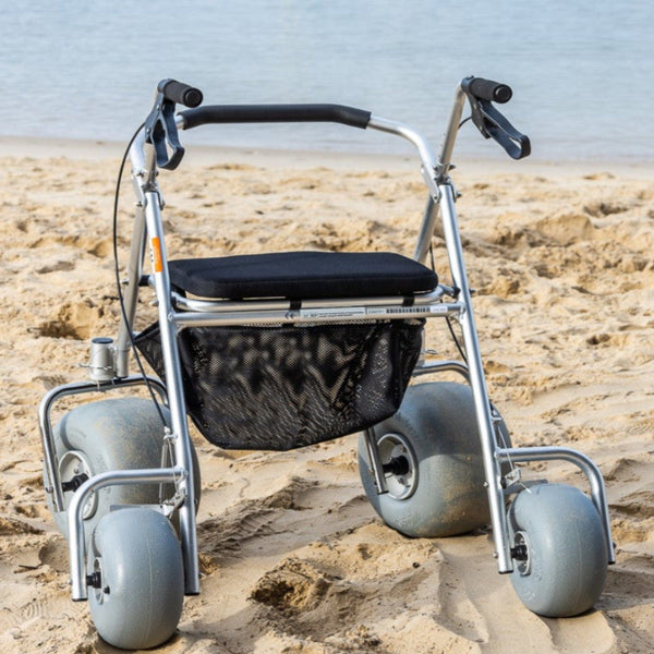 Wheeleez All-Terrain Beach Rollator Rear View With Polyurethane Wheels, Foam Handles, And A Mesh Storage Compartment, Displayed On A Sandy Beach.