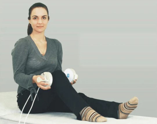 Woman Sitting On A Table With The Almagia International ALMAG-2 PEMF Therapy Device