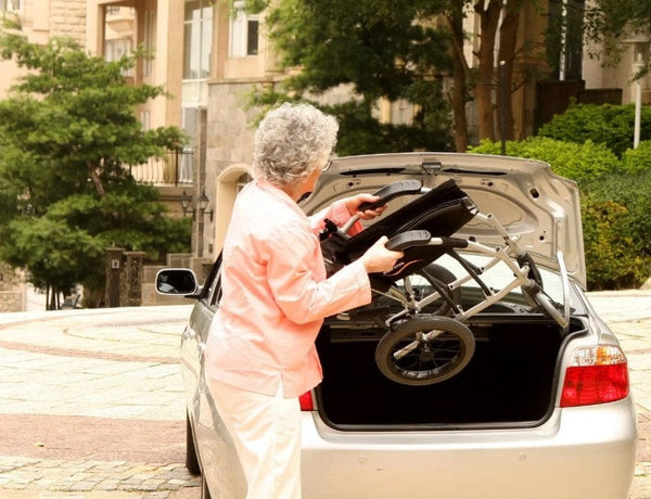 Rear View Of A Woman Transporting The Karman Ergo Lite Transport Wheelchair In Her Car's Trunk