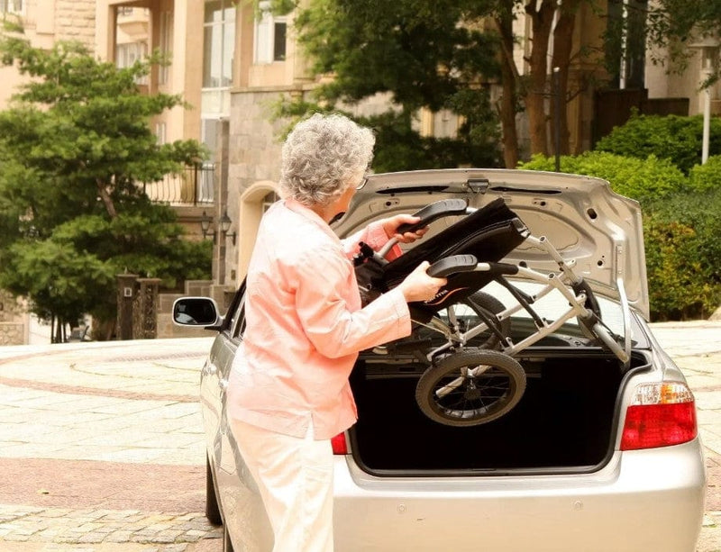 Rear View Of A Woman Transporting The Karman Ergo Lite Transport Wheelchair In Her Car's Trunk