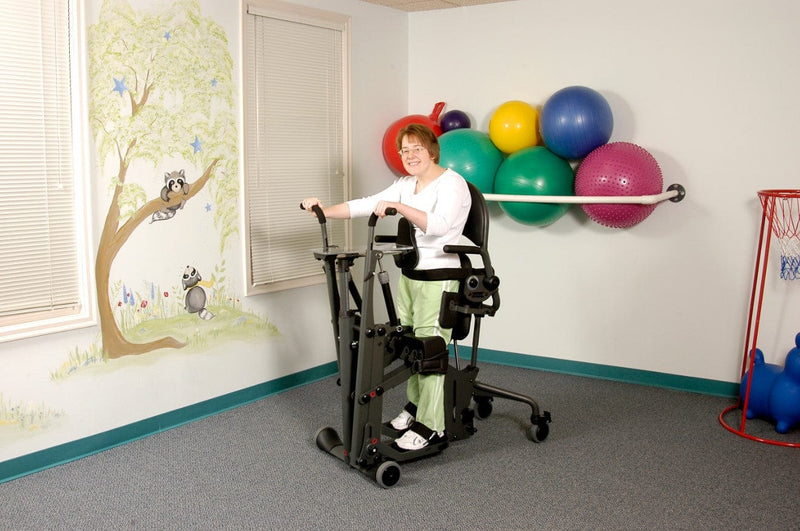 Side View Of A Woman Operating The EasyStand Glider Medium In A Care Facility Setting