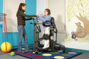 Side View Of The EasyStand Glider Medium Shown With Woman Using The Device And Another Woman Assisting Her In A Care Facility Setting