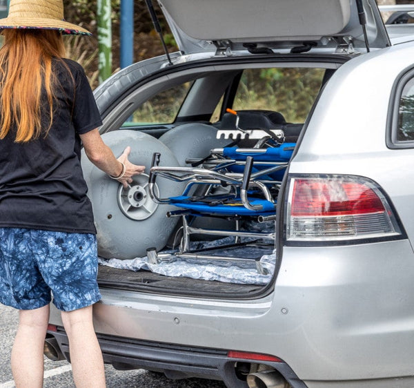 Wheeleez Sandcruiser All-Terrain Beach Wheelchair Mediterranean Blue Color Being Positioned Inside The Trunk Of A Car.