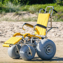 Wheeleez Sandpiper All-Terrain Beach Wheelchair Front View Yellow And Silver Color With Large Wheels Designed For Children And Small Adults On A Sandy Beach.