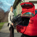 Woman Lifting The Feather Wheelchair Into The Trunk Of Her Car In The Driveway