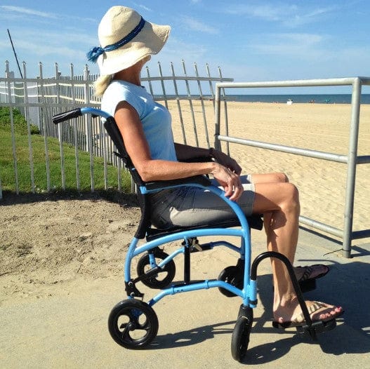 Woman Sitting In The Strongback Excursion 8 Lightweight Transport Chair Looking Out At The Ocean In A Beach Setting
