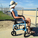 Woman Sitting In The Strongback Excursion 8 Lightweight Transport Chair Looking Out At The Ocean In A Beach Setting