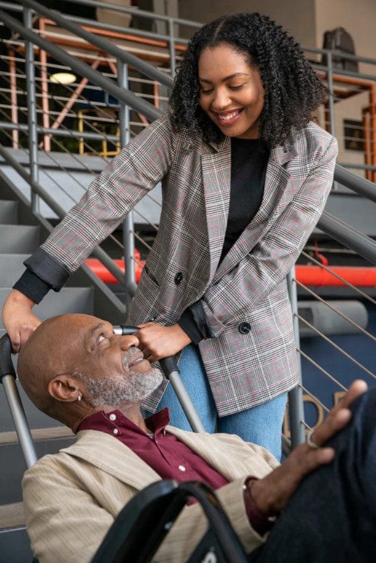 Woman Smiling As She Assists An Elderly Man Up The Stairs Using The Atlas Stair Climbing Wheelchair Lift